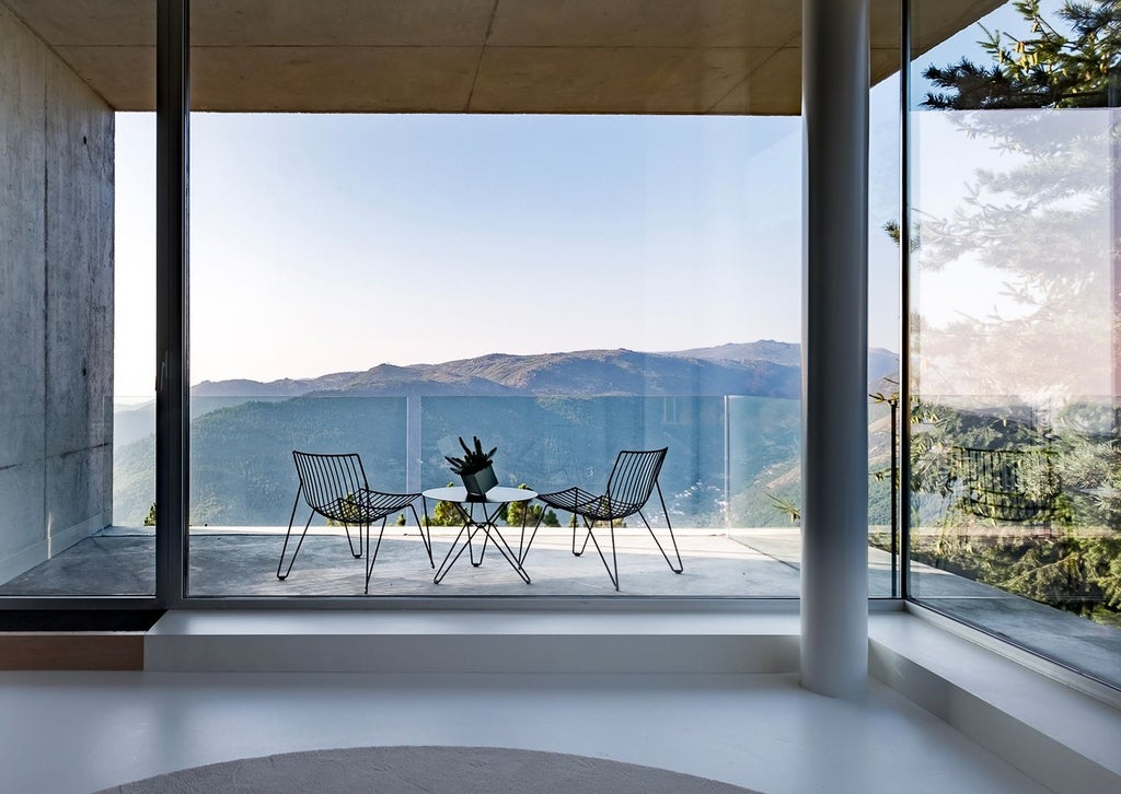 Elegant Portuguese luxury hotel room with panoramic mountain views, modern minimalist design, plush white bedding, and floor-to-ceiling windows overlooking scenic landscape