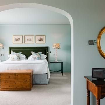 Luxurious garden room at Chewton Glen Hotel & Spa, featuring elegant decor, plush bedding, and large windows overlooking lush greenery in the United Kingdom.