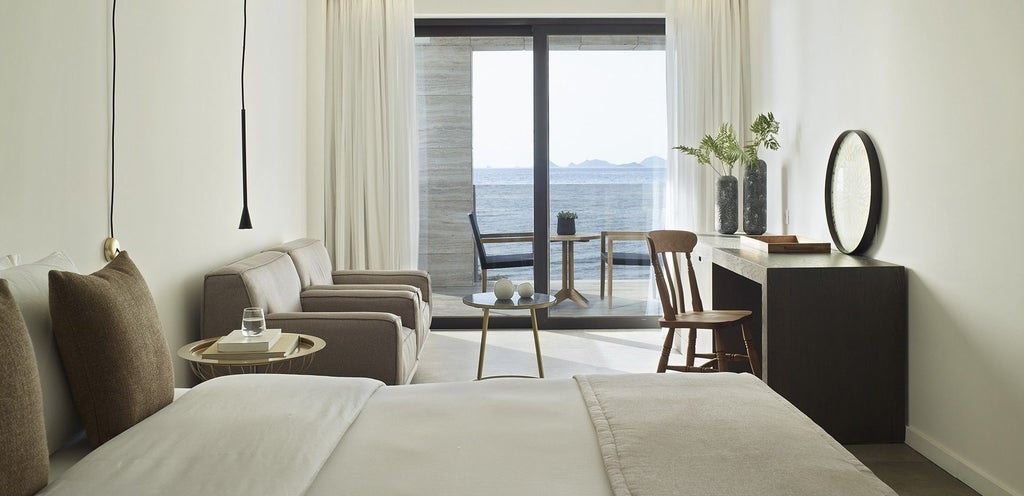 Spacious junior suite with panoramic Aegean Sea view, modern minimalist design, crisp white decor, and elegant contemporary furnishings in Greek coastal hotel