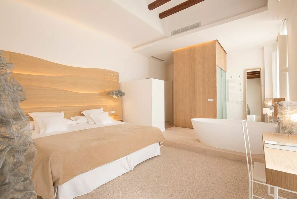 Elegant Doble Deluxe hotel room with minimalist design, soft lighting, crisp white linens, and wooden accents in historic Convent de la Missió, Spain