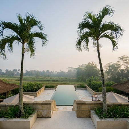 Luxurious stone pavilion with ornate domed roof overlooking tropical valley at sunset, inspired by ancient Buddhist temple architecture