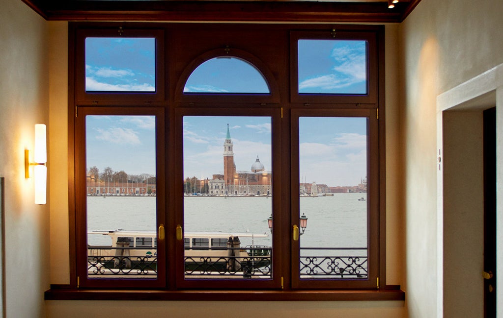 Elegant waterfront hotel in Venice with Gothic architecture, featuring stone arches, ornate windows and a grand entrance onto a canal