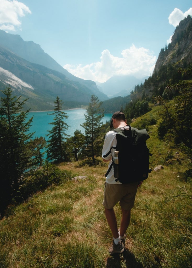 Scenic Swiss hiking trail overlooking crystal-clear Lake Lucerne, surrounded by snow-capped Alpine peaks and lush green mountain slopes at golden hour