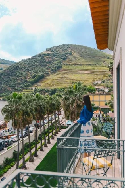 Elegant Portuguese hotel with stone facade, white-framed windows, and rustic terracotta roof nestled in a charming, historic landscape at sunset