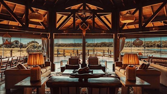 Luxurious private villa nestled in Brazilian wetlands, featuring rustic wooden interiors, expansive windows overlooking lush landscape, and elegant wildlife-inspired decor