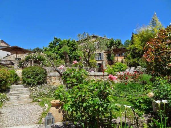 Elegant French countryside hotel with stone facade, manicured lavender gardens, and soft morning light casting a warm glow on the rustic architecture.