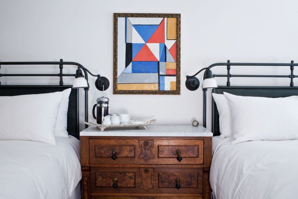 Elegant two-queen hotel room with modern design, crisp white linens, wooden accents, and minimalist decor in a refined boutique scenset setting.