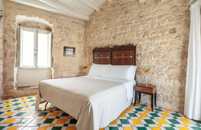 Rustic stone terrace of a boutique hotel in Modica, Sicily, with traditional architecture, lavender plants, and panoramic countryside views at sunset