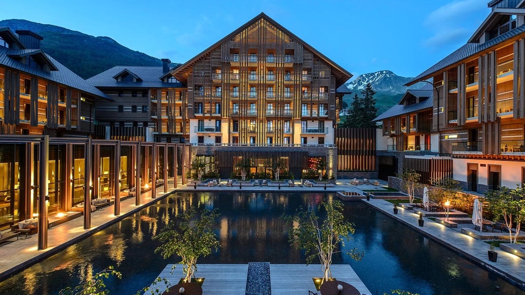 Luxurious alpine hotel with modern Swiss design, featuring wooden accents, floor-to-ceiling windows overlooking snow-capped mountains near Andermatt, Switzerland.