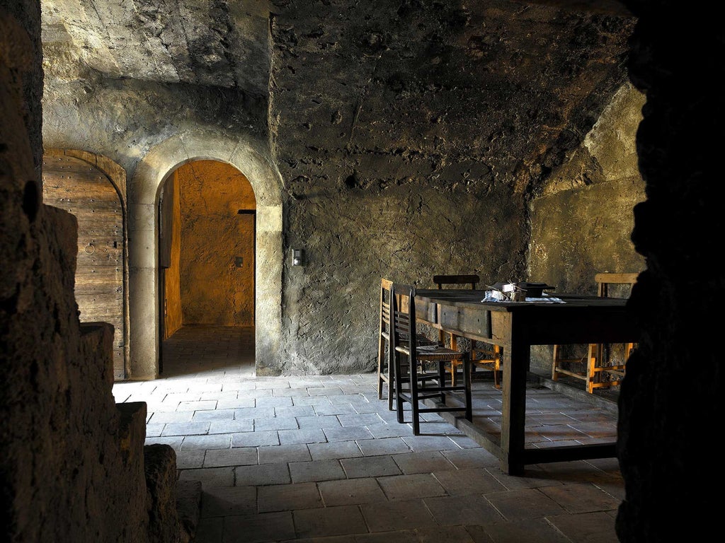 Rustic stone walls, handcrafted wooden furniture, soft candlelight illuminating a traditional Italian alpine hotel room with minimalist elegance