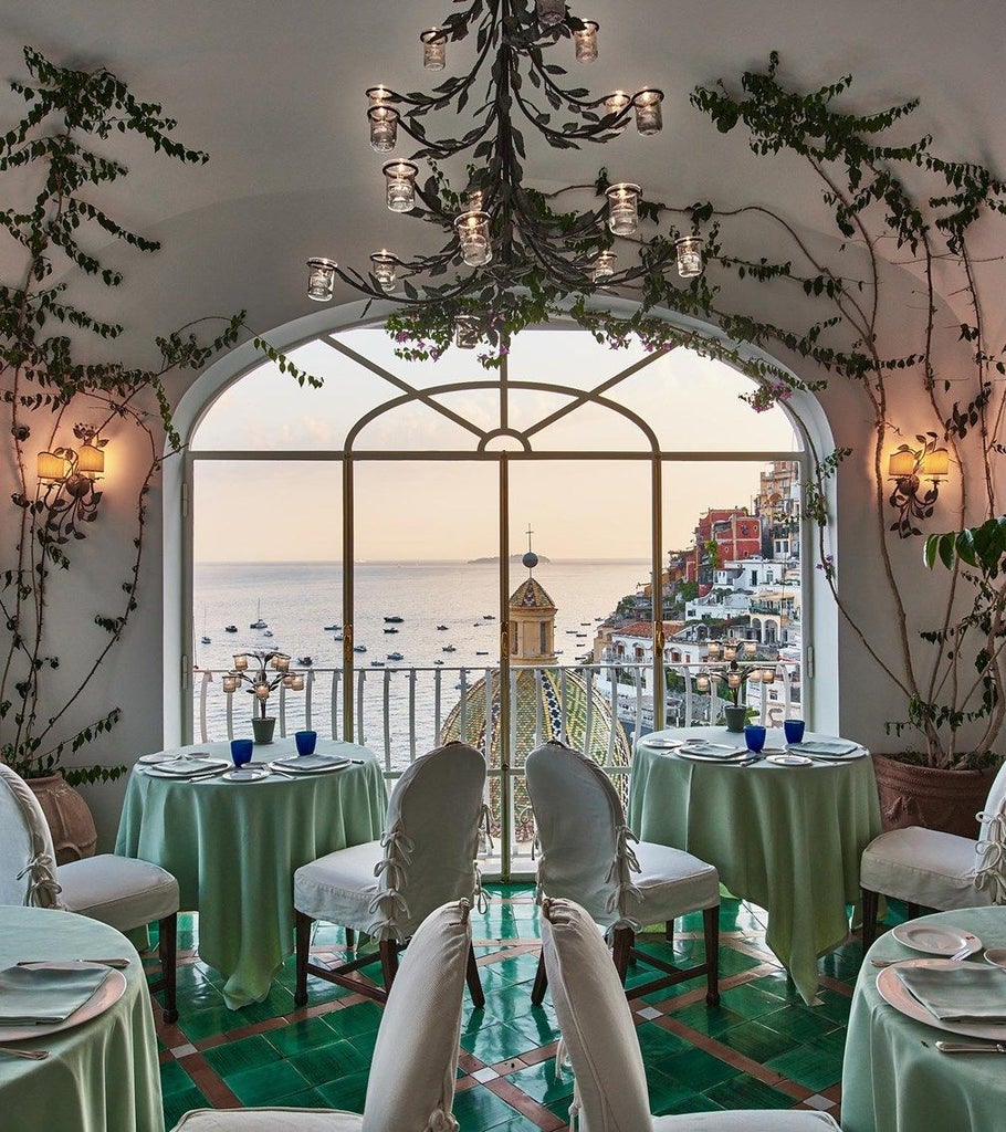 Elegant private terrace overlooking Positano's cliffside and Amalfi Coast, with Mediterranean-blue waters and luxury lounge seating at sunset