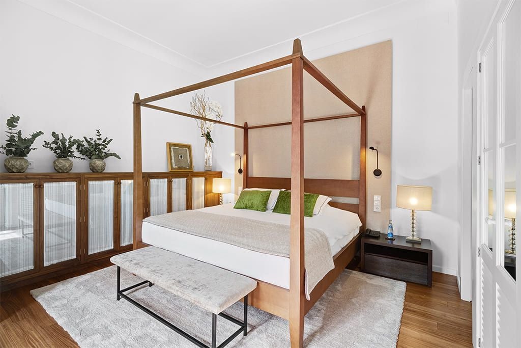 Elegant junior suite in Sóller, Spain, featuring crisp white linens, minimalist decor, wooden floors, and large windows with soft natural light