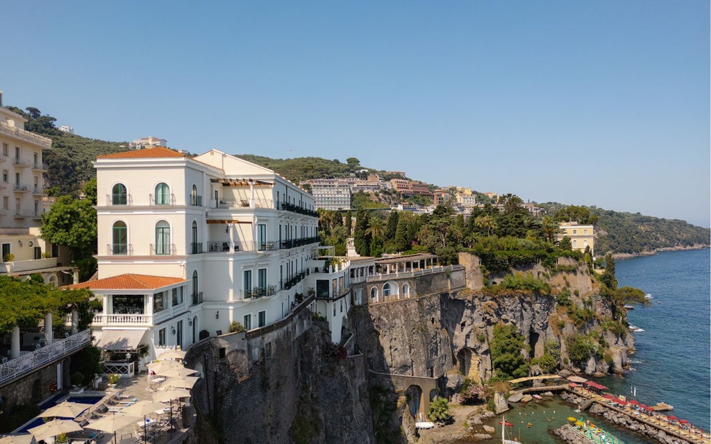 Luxurious terrace of Hotel Syrene overlooking dramatic Sorrentine coastline, with elegant Mediterranean architecture and azure sea backdrop