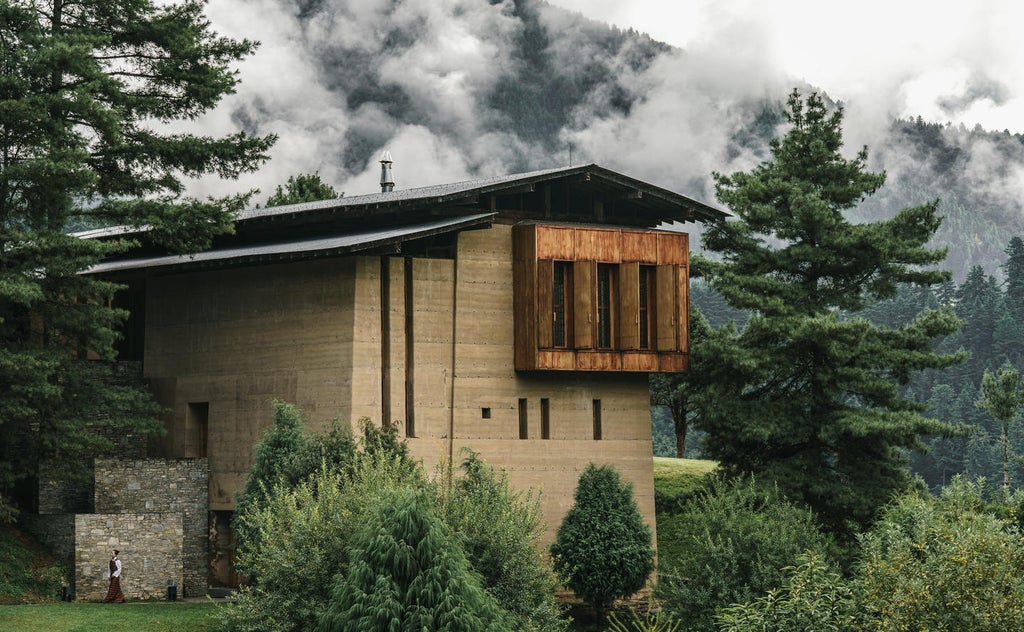 Luxurious mountain lodge with floor-to-ceiling windows overlooking misty Bhutanese valley, featuring modern timber architecture and cozy deck