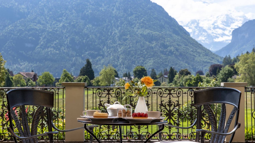 Elegant white Belle Époque hotel with ornate facade nestled against dramatic Swiss Alps, featuring grand balconies and manicured gardens