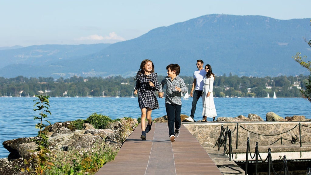 Luxurious lakeside hotel with modern glass architecture, nestled against Swiss Alps backdrop, reflecting elegance of La Réserve Genève Hotel and Spa's pristine waterfront setting