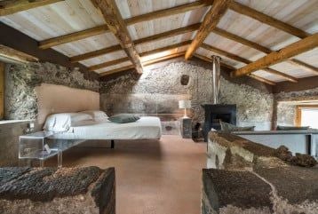 Elegant junior suite at Monaci delle Terre Nere with Mount Etna view, featuring minimalist design, warm wood tones, and luxurious white linens