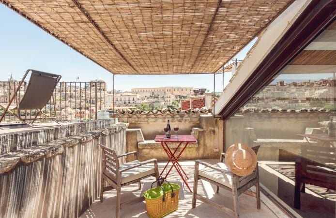 Luxurious Italian boutique hotel room with warm terracotta tones, rustic wooden furnishings, and elegant minimalist design overlooking scenic landscape