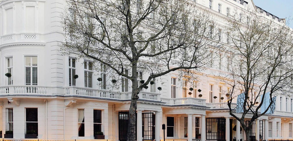 Elegant exterior of luxury hotel with classic British architecture, grand façade, and manicured entrance featuring white columns and pristine landscaping