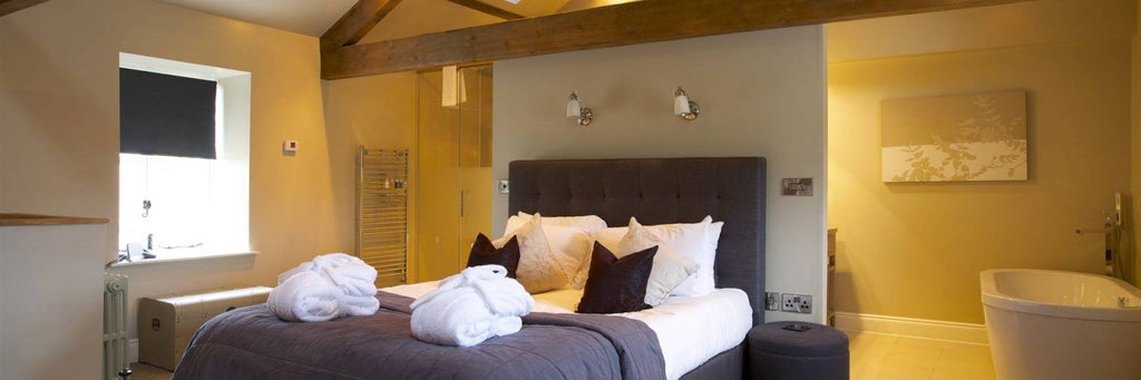 Elegant barn suite with exposed wooden beams, plush king bed, and contemporary styling in a luxurious countryside accommodation at scenset retreat.