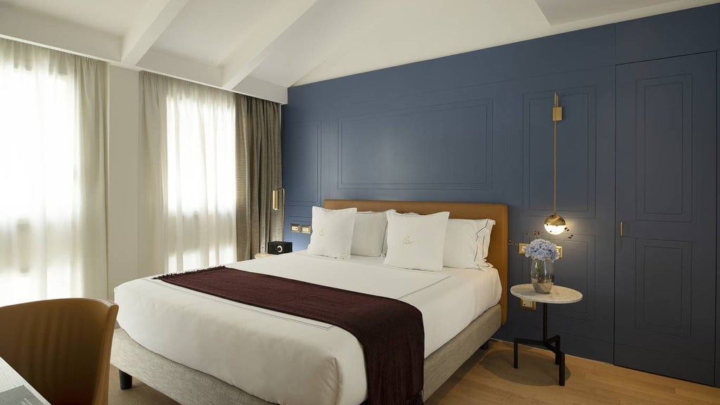 Luxurious hotel suite with elegant marble floors, contemporary Italian design, plush king bed, and soft neutral color palette in boutique Rome accommodation