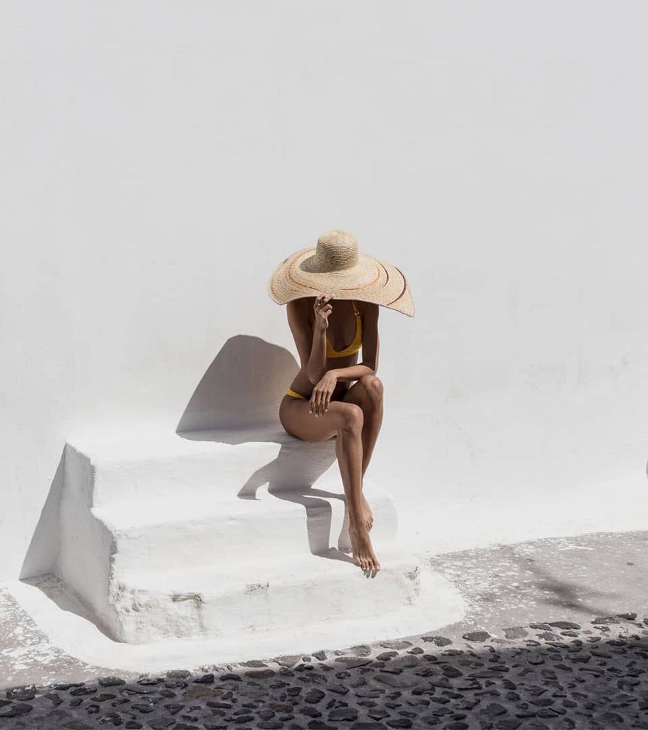 Elegant white-washed Cycladic classic suite with minimalist design, blue-trimmed balcony overlooking Santorini's iconic azure waters and volcanic landscape