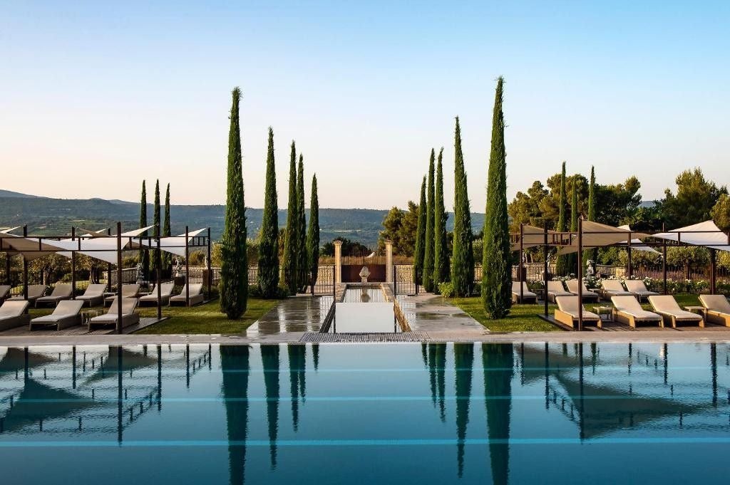 Elegant Provençal luxury resort with stone buildings nestled among vineyards, featuring a panoramic terrace and manicured gardens