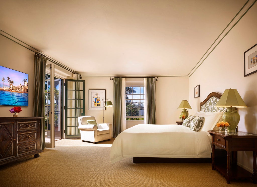 Spanish colonial-style luxury hotel with white stucco walls, red tile roofs, and lush palm gardens overlooking the Pacific Ocean beachfront