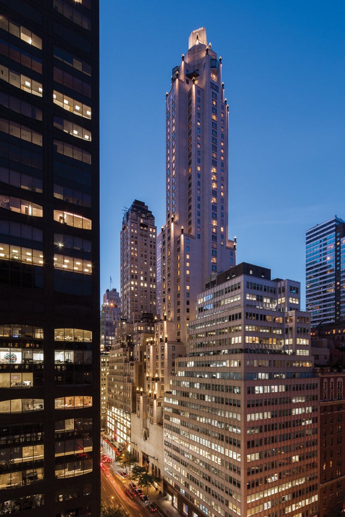 Art Deco-style luxury hotel with sleek glass tower soaring 52 stories above Manhattan, featuring bronze and limestone facade details