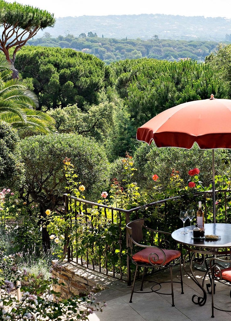 Luxurious beachfront villa with azure Mediterranean backdrop, white-washed walls, lush tropical gardens, and elegant French Riviera architectural style at Saint-Tropez resort