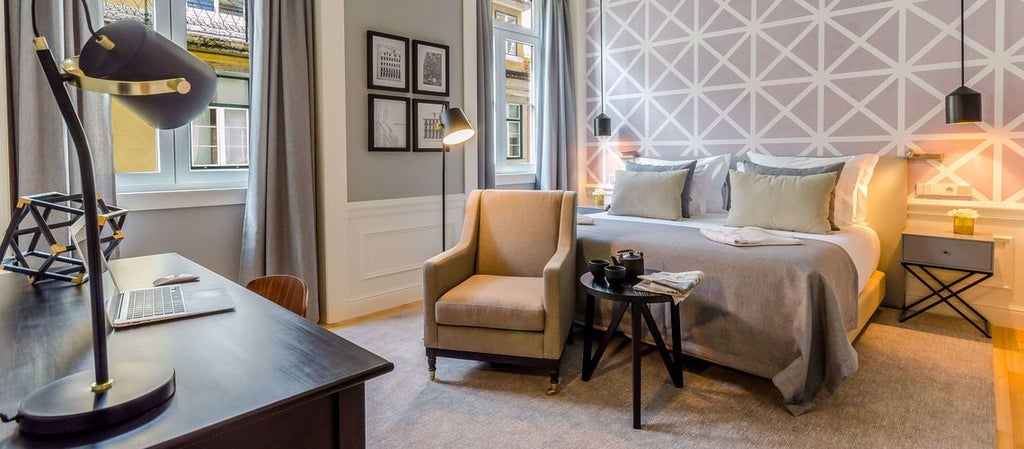 Classic hotel room with elegant Portuguese design, plush white bedding, hardwood floors, and large windows overlooking charming downtown cityscape in Porto