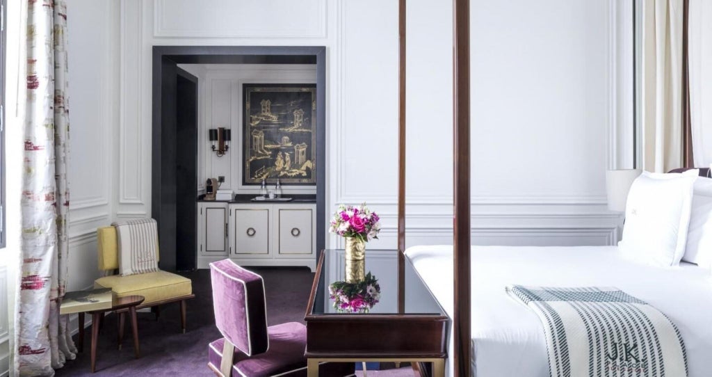 Elegant Paris hotel room with plush cream-colored furnishings, soft lighting, modern French design, and sophisticated minimalist decor in muted tones