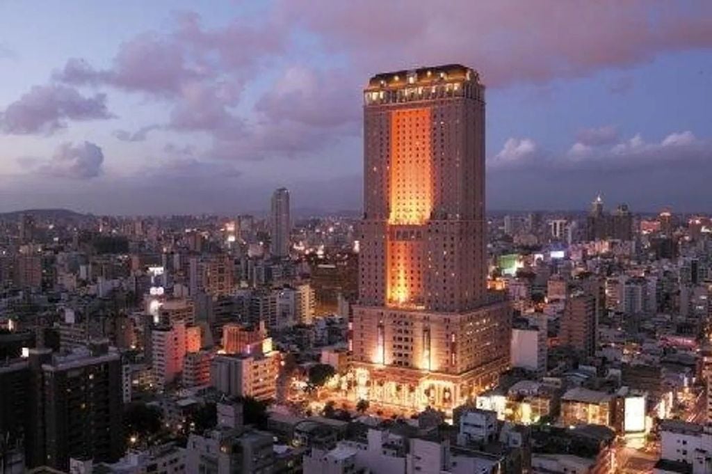 Elegant 85-story luxury hotel tower in Kaohsiung with glass façade, illuminated at dusk, dominating the city skyline against purple sky