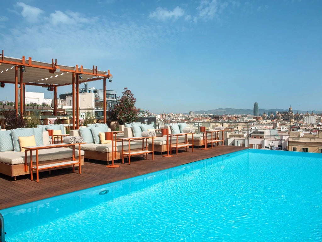 Elegant marble lobby of luxury hotel with crystal chandeliers, sleek design, and panoramic windows overlooking Barcelona's historic cityscape