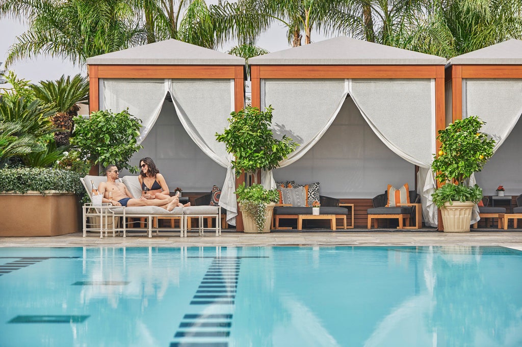 Modern luxury hotel facade with palm trees, featuring Mediterranean-style architecture, elegant balconies and manicured gardens