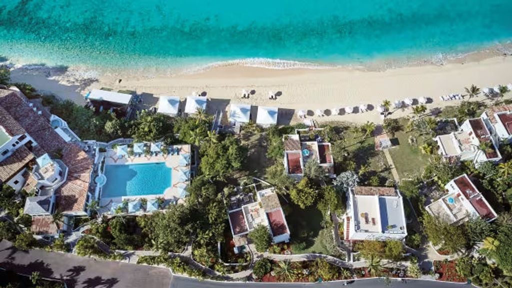 Elegant beachfront resort with white Mediterranean-style villas nestled on pristine sandy beach, overlooking turquoise Caribbean waters