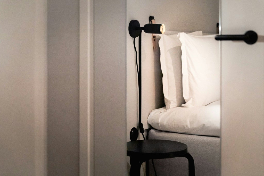 Minimalist Scandinavian hotel room with crisp white linens, warm wood accents, sleek design, and ambient lighting at Blique by Scenset in Sweden