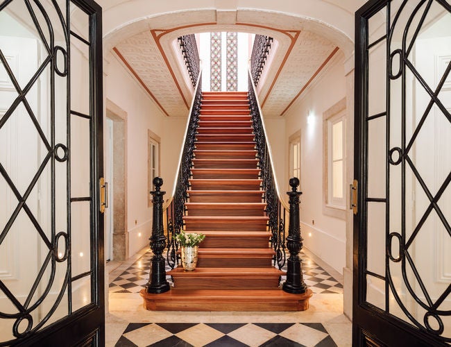 Elegant five-star Portuguese palace hotel with ornate white facade, arched windows, manicured gardens and grand marble entrance steps