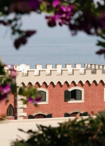 Historic watchtower hotel perched on cliffside overlooking private bay in Gulf of Naples, surrounded by pine woods and coasta