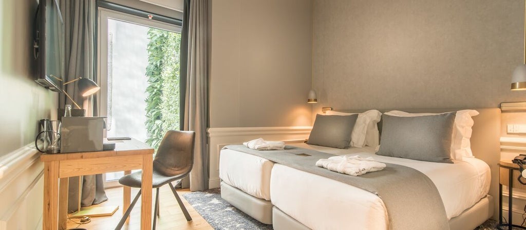 Elegant classic-style hotel room with soft neutral tones, large windows overlooking scenic urban landscape in Porto's historic downtown district