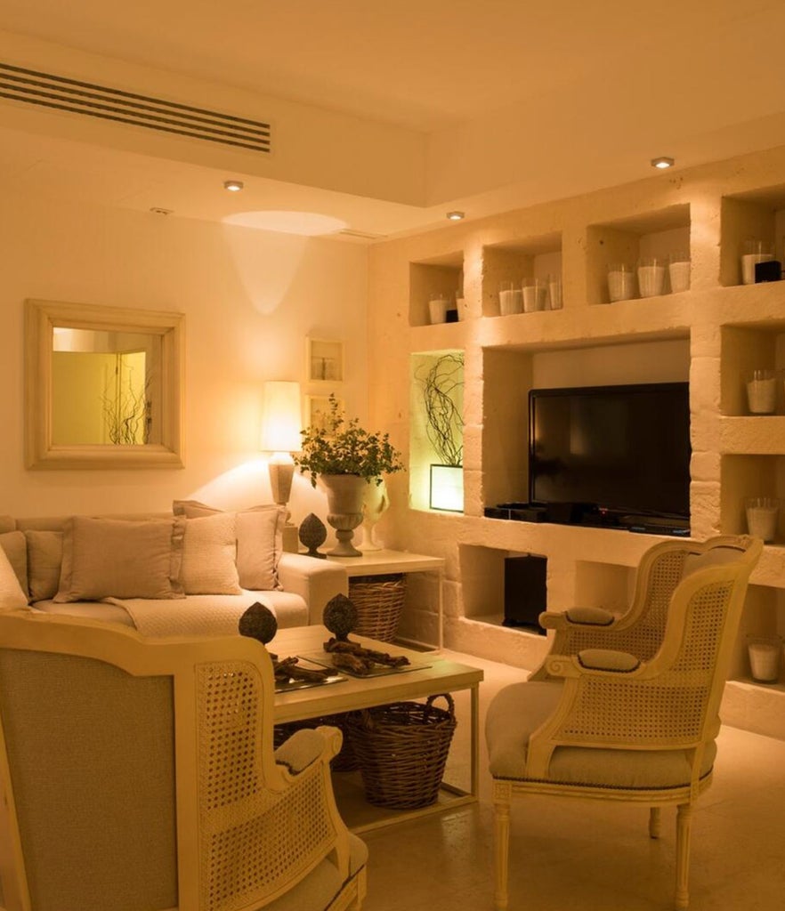 Elegant Mediterranean hotel room with vaulted stone ceiling, white linens, rustic wooden furniture and local artisanal decor details