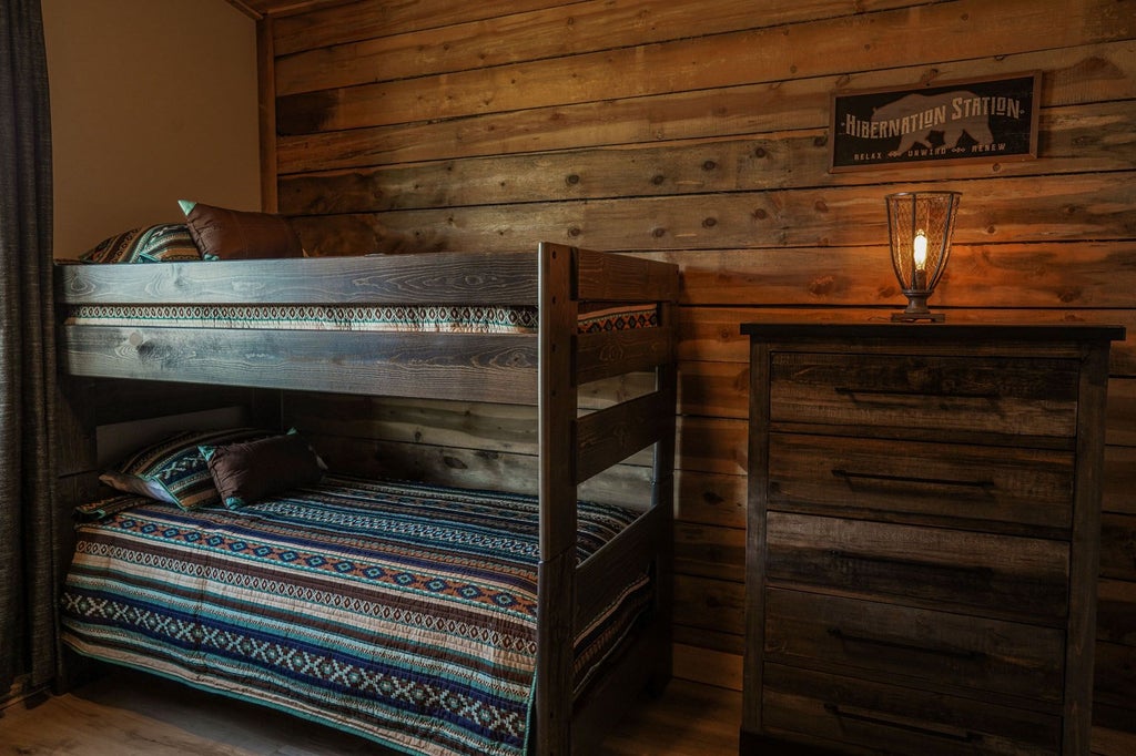 Spacious lodge room at Scenset Mountain Ranch with rustic wooden furnishings, plush bedding, and panoramic mountain views through large windows in United States