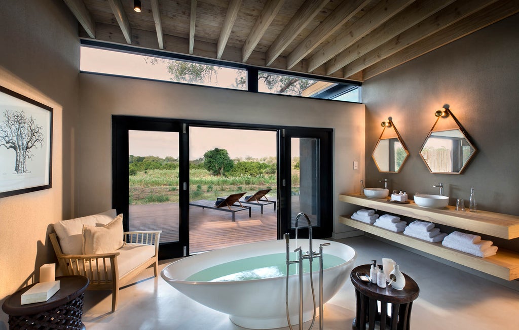 Private deck with infinity pool overlooking African savanna at Lion Sands River Lodge, modern luxury suite visible through glass doors