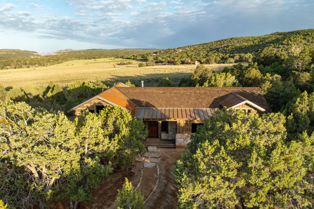 Rustic lodge bedroom with king-sized bed, wooden furniture, and large windows overlooking scenic mountain landscape at remote ranch in western United States