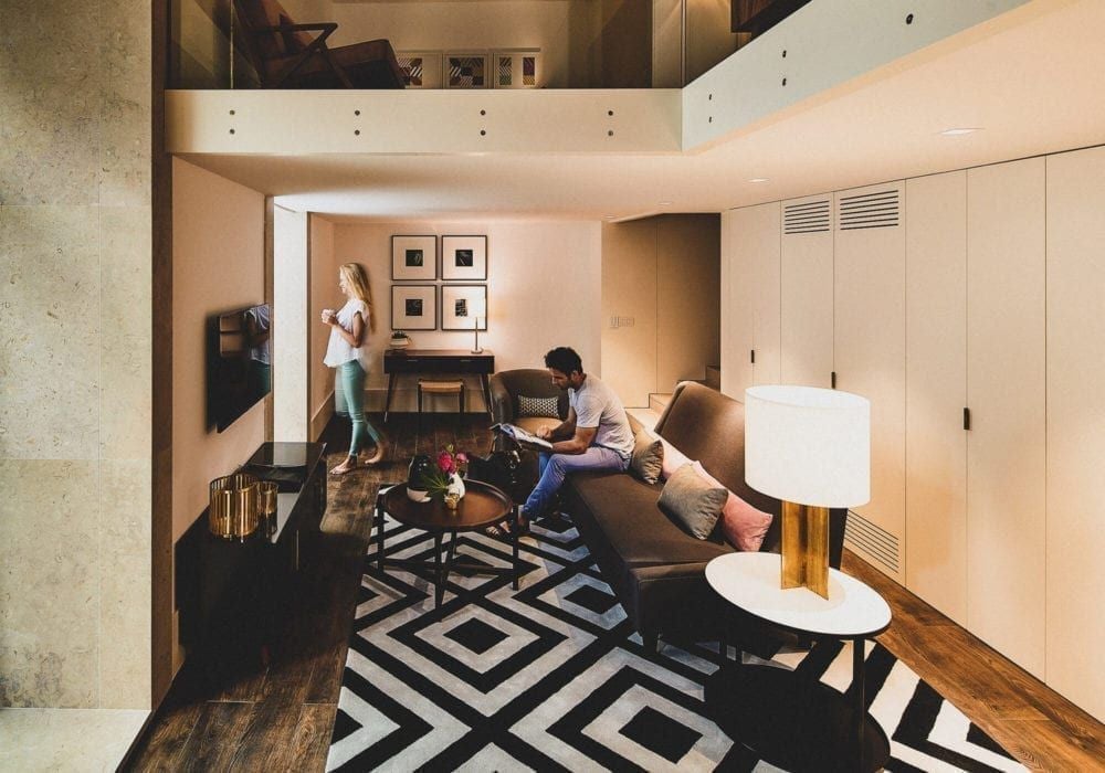 Elegant mezzanine suite at boutique hotel, featuring plush white bed, minimalist wooden furniture, and warm ambient lighting in Bairro Alto, Lisbon