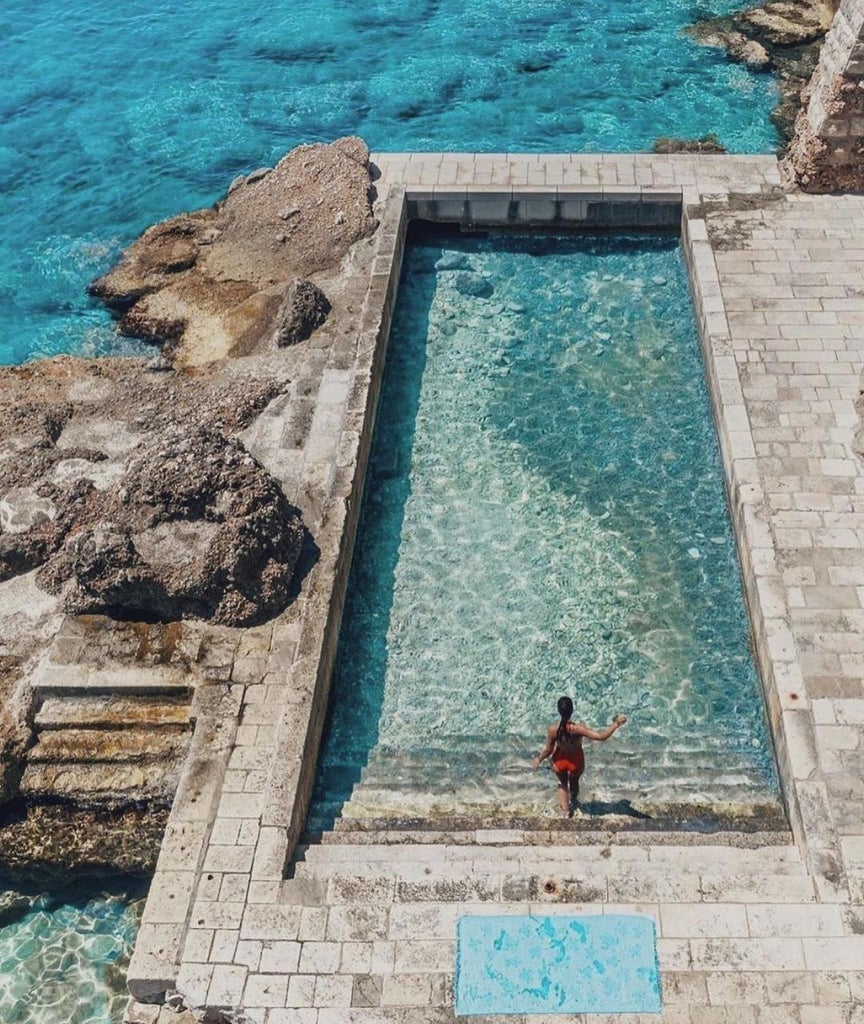 Grand Hotel Excelsior facade rising above Adriatic Sea in Dubrovnik, featuring Mediterranean architecture with beige walls and private beach