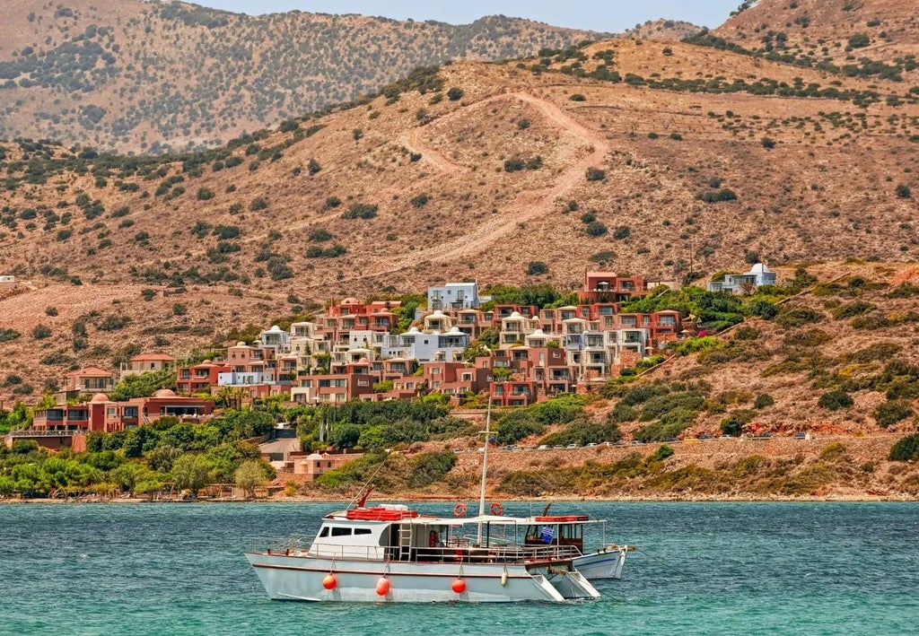 Panoramic view of luxurious white-domed resort overlooking azure Aegean Sea with private villas nestled on Crete's scenic coastline