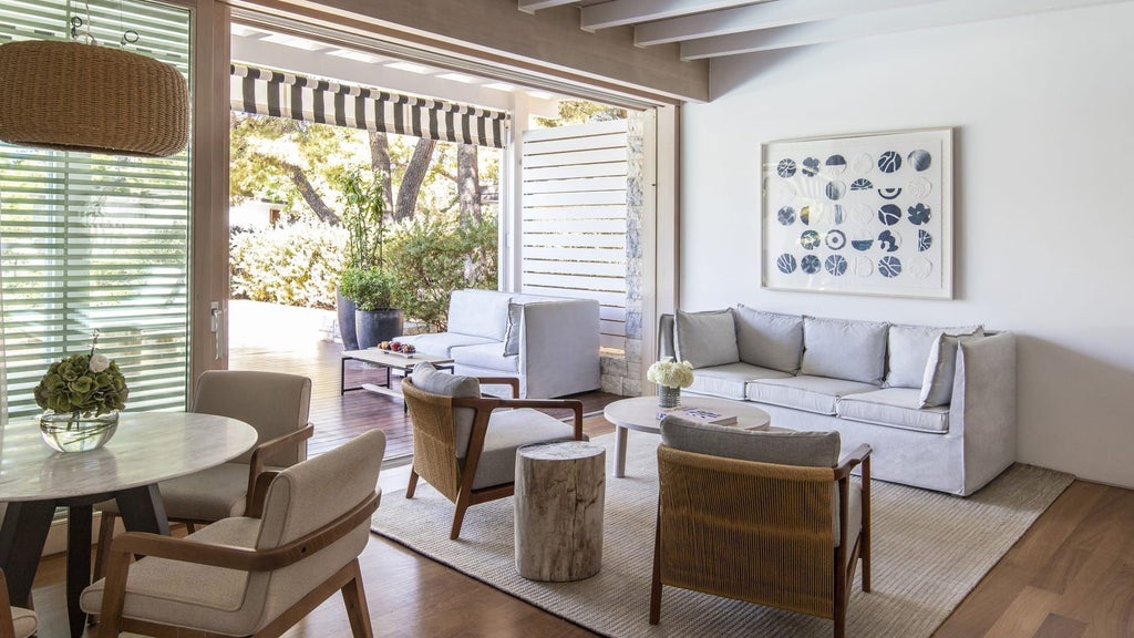 Elegant bungalow suite overlooking private pool and Mediterranean garden, featuring modern furnishings and floor-to-ceiling windows