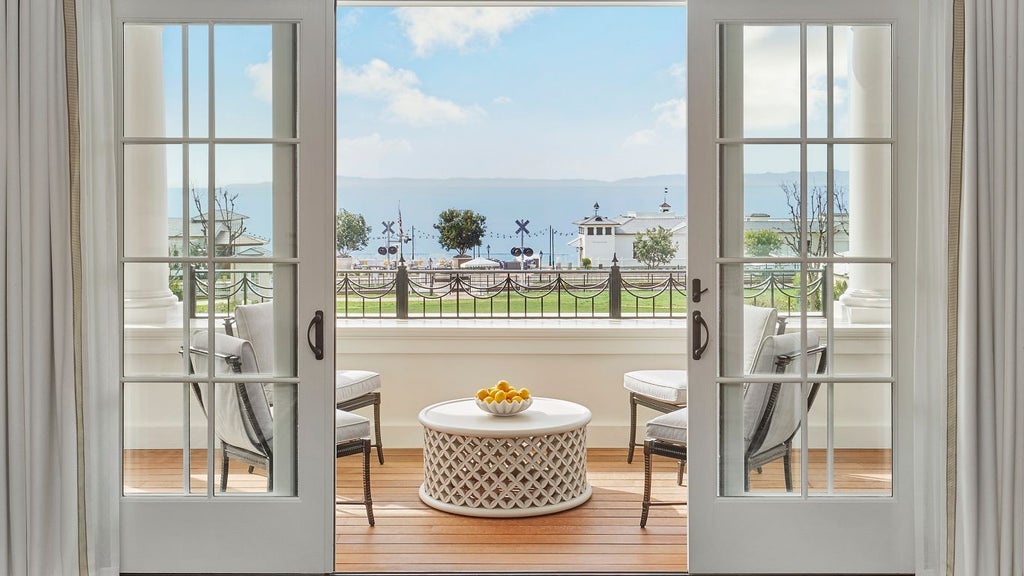 Luxurious ocean-view terrace with elegant outdoor seating, white daybeds, and panoramic coastal scenery of Rosewood Miramar Beach resort in California