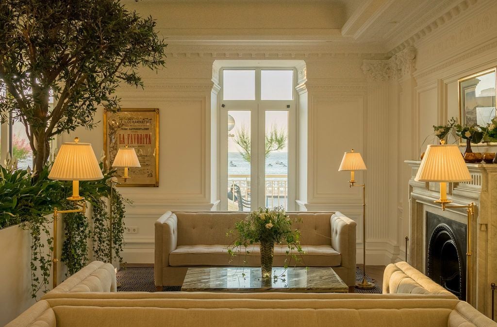 Historic Mediterranean villa hotel with white facade, arched windows, and manicured gardens overlooking the Spanish coastline at sunset